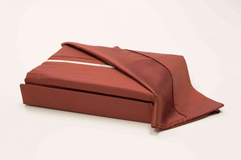 A 100% Long staple egyptian cotton sheet set including pillow cases in a rust or terracotta red color in an alternate angle